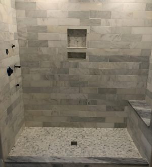 A modern shower featuring elegant marble tile and a sleek glass door.