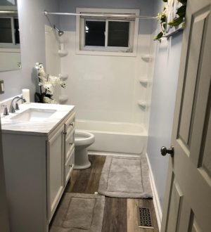 Small bathroom featuring a toilet, sink, and shower, with neutral-colored walls and minimalistic decor.