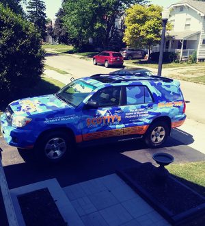 A blue SUV parked beside a house, showcasing its side profile against the residential backdrop.