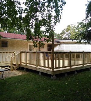 A wooden deck featuring a table and chairs set in a grassy yard, ideal for outdoor dining and relaxation.