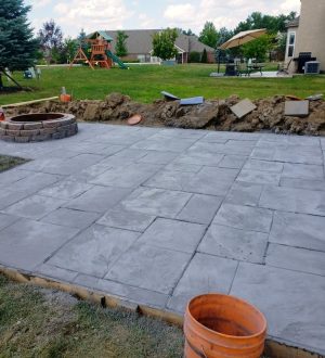 A concrete patio featuring a fire pit surrounded by a bucket, ideal for outdoor gatherings and relaxation.