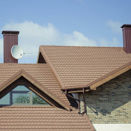 A roof featuring a satellite dish mounted on top, set against a clear blue sky.