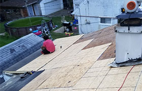 A man is climbing a ladder to work on a roof, wearing safety gear and focused on his task.